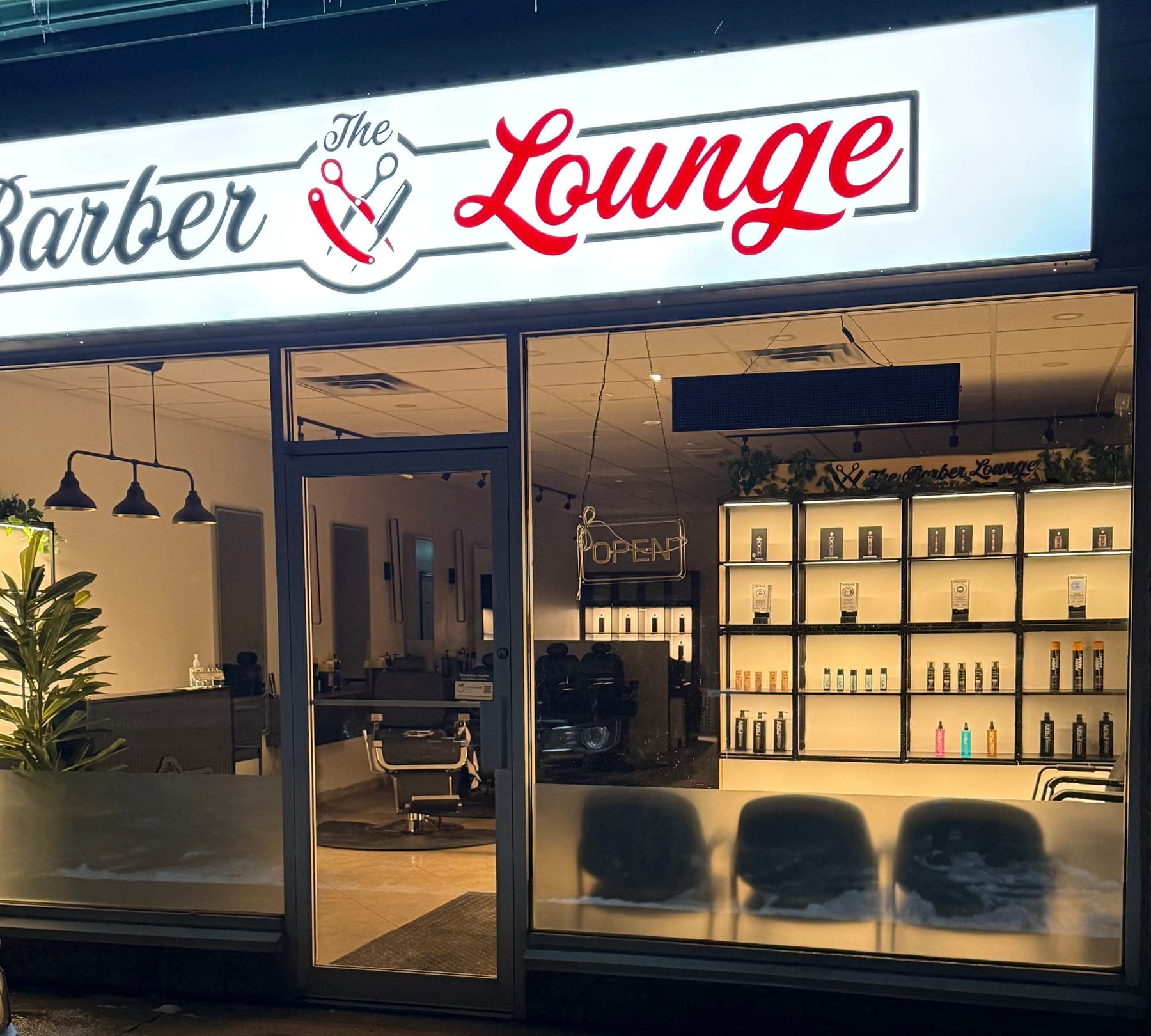The Barber Lounge Downey Rd storefront lit up at dusk